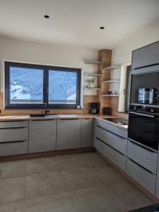 维尔德科格尔山麓布兰贝格Apartment Talblick的带不锈钢用具的厨房和2个大窗户