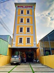 Ấp Trà KhaSơn Tùng Motel的一座黄色的建筑,前面有一辆汽车