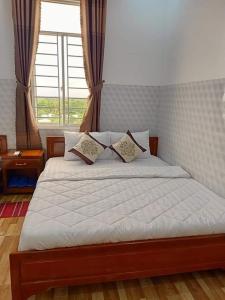 Ấp Trà KhaSơn Tùng Motel的一间卧室配有一张带白色床单的床和一扇窗户。