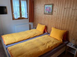 格施塔德Alpenchalet Spiher Gstaad Ferienwohnung im Parterre的一间卧室设有两张带黄床单的床和窗户。