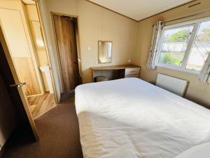 本布里奇2 Bedroom Caravan CW111, Whitecliff Bay, Bembridge, Isle of Wight的一间小卧室,配有白色的床和窗户