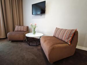 波兹南Platinum Apartments Aparthotel的客厅配有两把椅子和墙上的电视