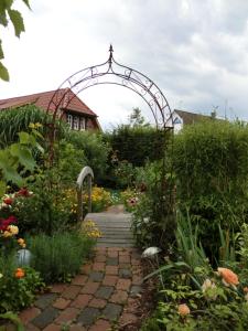 霍登哈根温馨家园酒店的一座带拱门和鲜花走道的花园