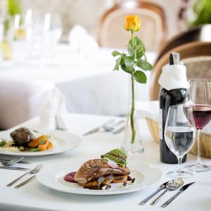 克罗斯诺波兰帕拉克酒店的一张桌子,上面放着两盘食物和一杯葡萄酒