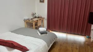 Nishi-tsurumaYSTY-HOTEL的一间卧室配有一张带书桌和红色窗帘的床