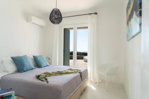 法纳里Villa Crystal by Mykonos Mood的一间卧室配有一张床、一张桌子和一个窗户。