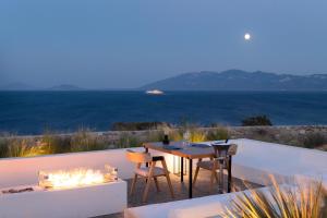 Ágios FokásKOIA All - Suite Well Being Resort - Adults Only的一个带桌椅的庭院和大海