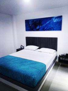 内瓦Onix Hotel的一间卧室配有一张带蓝色毯子的大床