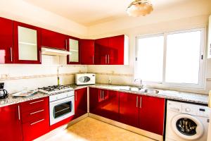 马赫迪耶Mahdia Place Apartments的厨房配有红色橱柜、水槽和窗户