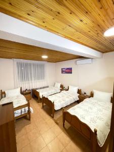 斯库台Shkodra Guest House的客房设有三张床和木制天花板。