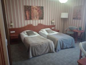 波兹南Biały Dom Henlex Hotel Restauracja的酒店客房设有两张床和一张桌子。