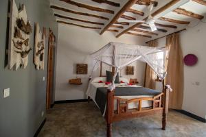MakunduchiNest Style Beach Hotel Zanzibar的一间卧室配有一张带天蓬的床