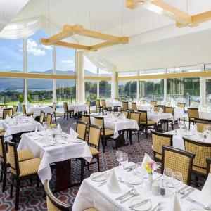 基拉尼Castlerosse Park Resort的餐厅设有白色的桌椅和窗户。