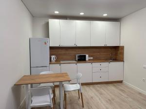 科克舍套ЖК Ауэзов的厨房配有白色橱柜和木桌及椅子