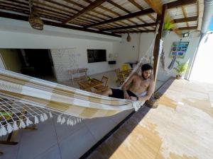 马拉戈日Barra Grande Pousada的坐在房子吊床上的男人