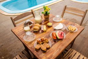 马拉戈日Barra Grande Pousada的一张木桌,上面有早餐食品和牛奶