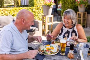 WestelbeersSummio Parc Duc de Brabant的坐在餐桌旁吃食物的男人和女人