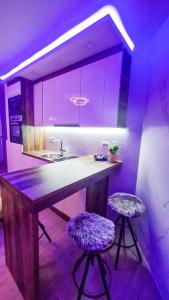 达鲁瓦尔Ginko sobe Daruvar的厨房配有紫色照明和带两个凳子的台面
