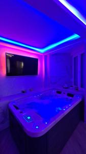 达鲁瓦尔Ginko sobe Daruvar的客房设有一个配备了电视和紫色灯的浴缸。