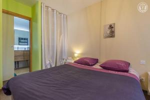 BassensA l'oree des monts的一间卧室配有一张带紫色枕头的大床