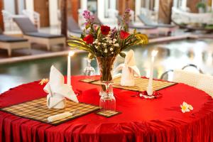 DalungNorth Wing Canggu Resort的红色的桌子,花瓶和蜡烛