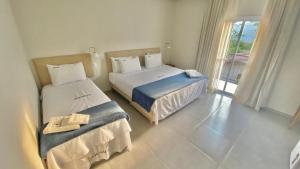 帕拉蒂Pousada Aquino Mar的酒店客房设有两张床和窗户。