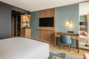 波尔图Renaissance Porto Lapa Hotel的酒店客房配有一张床、一张书桌和一台电视。
