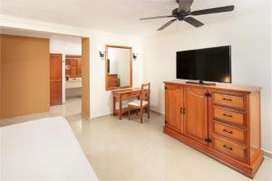艾库玛尔El Dorado Seaside Palms, Catamarán, Cenote & More Inclusive的卧室配有木质梳妆台上的平面电视。