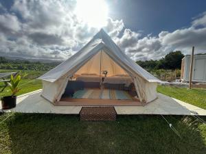拉耶Maleka Farm: Tent Glamping North Shore Oahu的田野上带床的白色帐篷