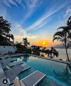乌巴图巴Catalina Hotel的一个带椅子的游泳池,享有日落美景