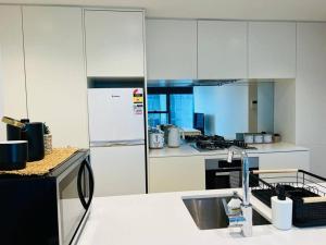 墨尔本2 BR Apartment Melbourne Square的厨房配有白色橱柜和水槽