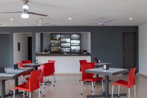 梅里达Hotel y Villas Costa del Sol的用餐室配有桌子和红色椅子