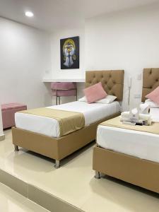 卡塔赫纳Hotel Hernández CTG的一间卧室配有两张床和一张桌子及椅子