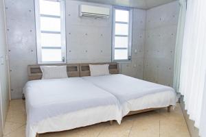 ShirahoShiraho Villa - Vacation STAY 20487v的卧室配有一张白色大床和两个窗户