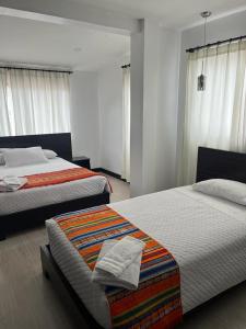 昆卡Hostal Entre Ríos的卧室设有两张床,拥有白色的墙壁和窗户。
