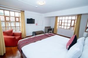 库斯科Inkarri Cusco的卧室配有白色的床和红色椅子