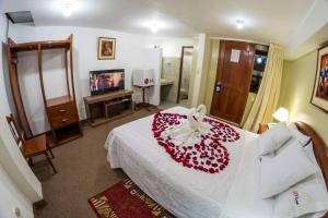 卡哈马卡El Cumbe Inn的一间卧室配有一张白色床,上面有红花