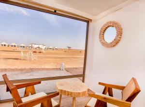 梅尔祖卡Sahara Royal Resort的客房设有带桌椅的大窗户。