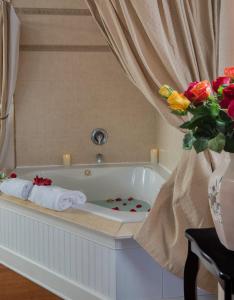 圣奥古斯丁Victorian House Bed and Breakfast的浴缸配有毛巾和花瓶