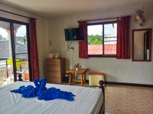 卡塔海滩Kata Lina guesthouse的一间卧室配有一张带蓝色床单的床和一扇窗户。