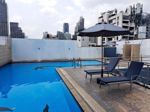 曼谷2A-2 Bedrooms3Bathrooms Downtown Bangkok Near Mrtbts的屋顶游泳池配有椅子和遮阳伞