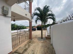 库马西Sigma Theta Homes - Kumasi Atimatim的一座带围栏的房子前面的棕榈树
