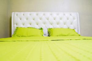 基加利The Vacation Homes Apartments的一张带绿色床单和两个绿色枕头的床