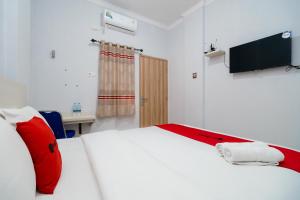邦加槟港RedDoorz at Homestay Lotus 2 Pangkal Pinang的一间卧室配有一张带红色枕头的白色床和电视。