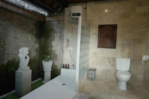 乌布New Mumbul Ubud的一间带卫生间和雕像的浴室
