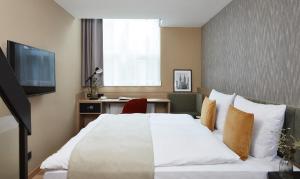 纽伦堡Living Hotel Nürnberg的一间卧室配有一张床、一张书桌和一台电视