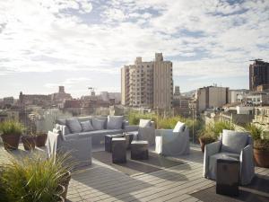 巴塞罗那尤尔板特拉法加酒店的一个带沙发和桌子的屋顶露台,并享有城市