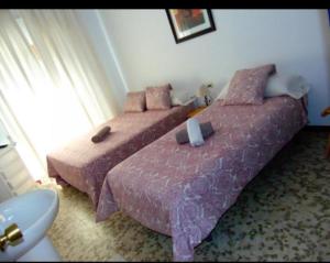 圣玛丽亚港Hostal Puerto de Santa Maria的一间卧室设有两张带粉色床单的床和窗户。