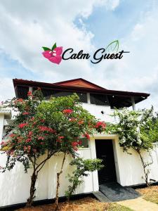 亭可马里Calm Guest的白色的建筑,上面有粉红色蝴蝶标志