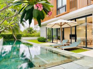富国Moon Villa Phu Quoc - 3 Bedroom - Private pool的一座带遮阳伞的房屋前的游泳池